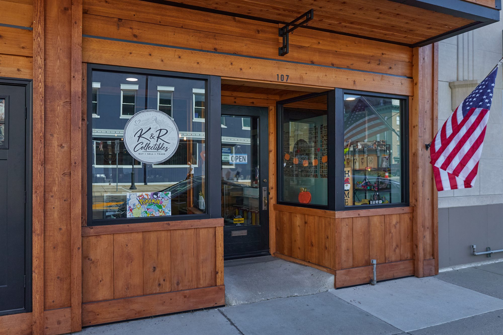 The K&R Collectibles storefront: cedar-wood front, round logo sign in the window, and an American flag by the door